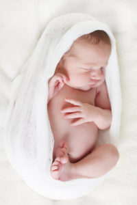 Newborn baby asleep on a blanket.